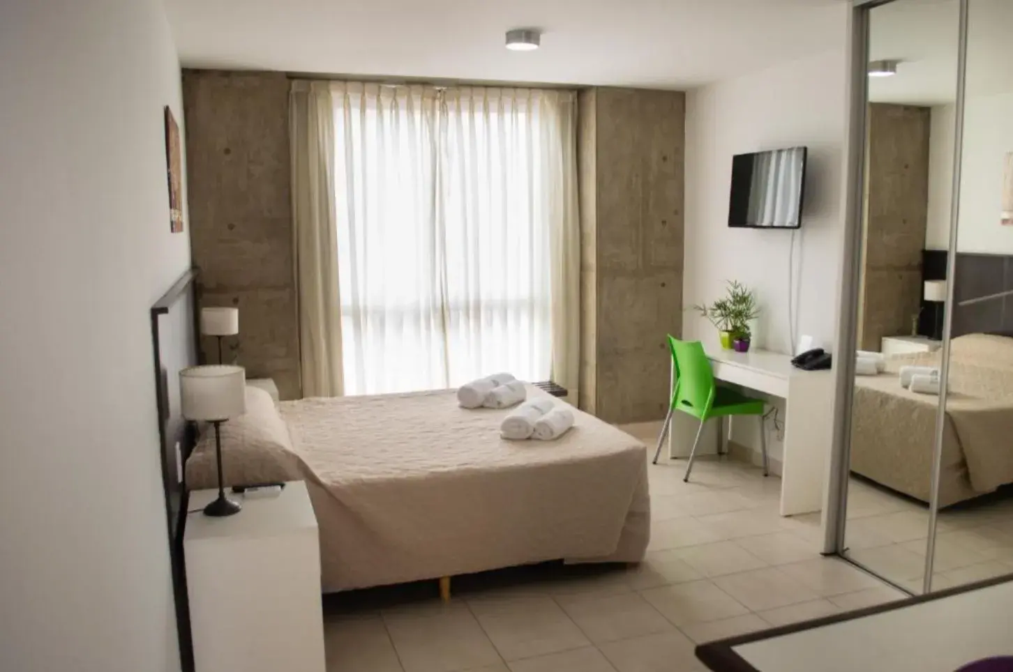 Dormitorio de Torre Potosí con cama, escritorio, TV y espejo